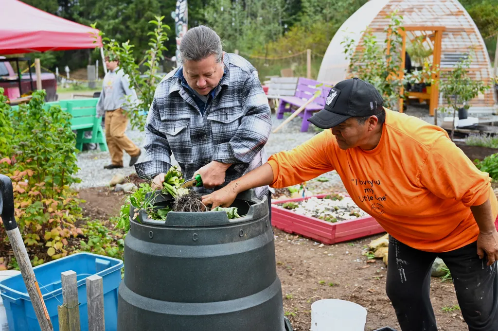 A pair of gardeners work to harvest fresh vegetables from an abundant community garden.