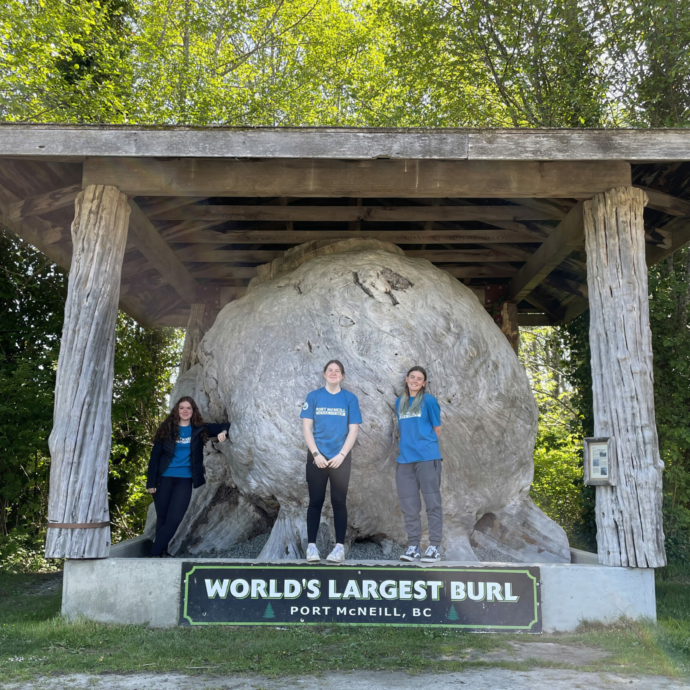 The Port McNeill tourism staff pose in front of the World's Largest Burl landmark on North Vancouver Island.