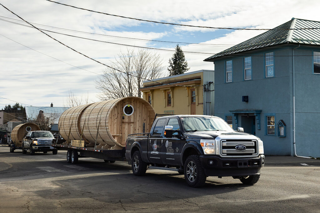 Three sleeping barrels - made on Vancouver Island - are trucked through Cumberland, BC.